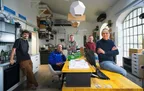 Das Team der Modellbauer in der Werkstatt, fünf Personen rund um den gelben Werktisch.